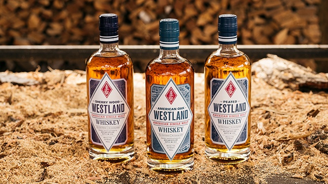 Bottles of Westland Sherry Wood, American Oak and Peated whiskies on a bed of sawdust