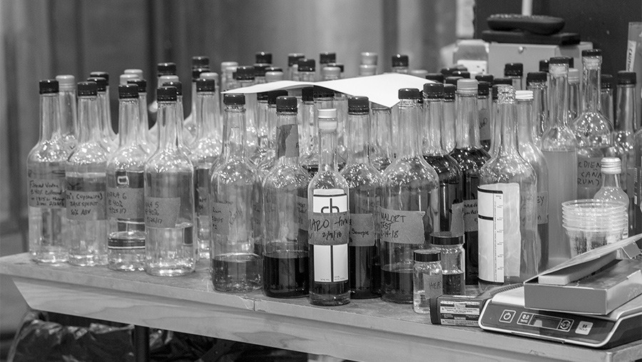 various bottles of alcoholic spirits with handwritten labels on a tabletop