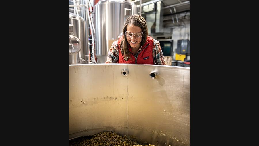 Odell Employee Colleen Rapaich smiles as she looks into a tank of unfermented beer
