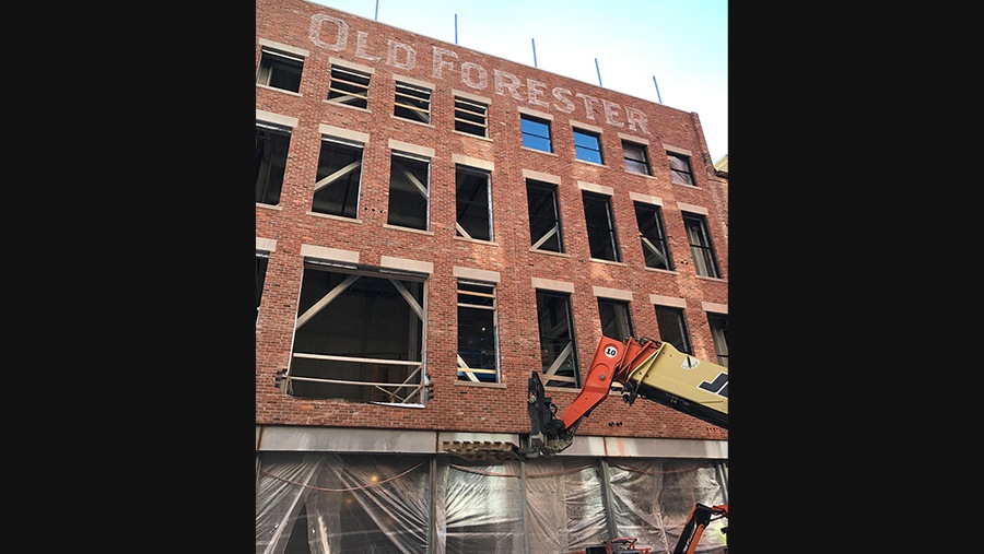 construction crane moves materials into a brick building