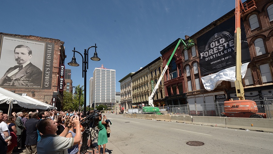 crowd of people watch as old forester coming soon banner is unveiled
