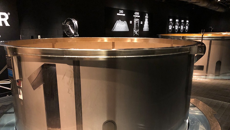 large steel cylindrical fermentation tank with metallic number one on side protruding through the floor