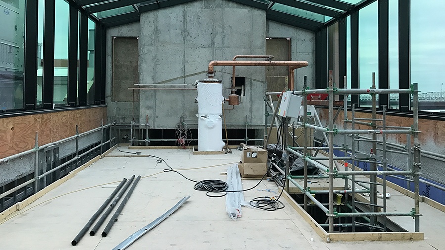 scaffolding and the top of a wrapped column still in a room with glass ceiling and windows