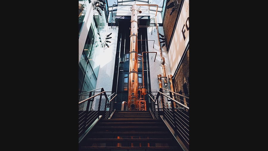 stairs leading up to a three-story tall copper column still used to distill alcohol