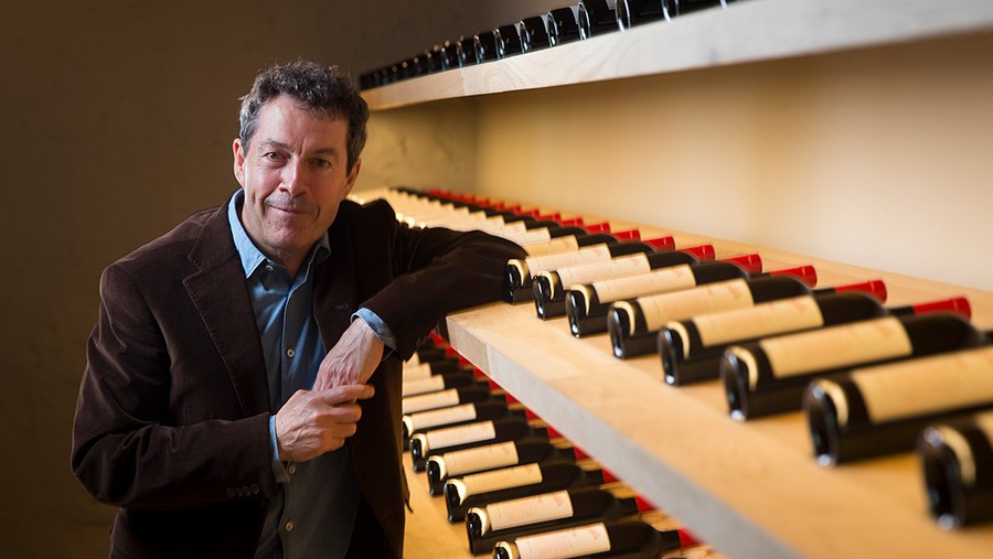 Penfold's Chief Winemaker, Peter Gago, leans one of many shelves lined with bottles of red wine 