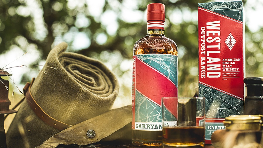 Bottle of Westland Outpost Range Garryana Whiskey on a table beside camping gear
