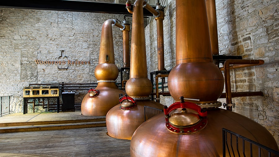 Three copper pot stills in a brick building with vaulted ceilings