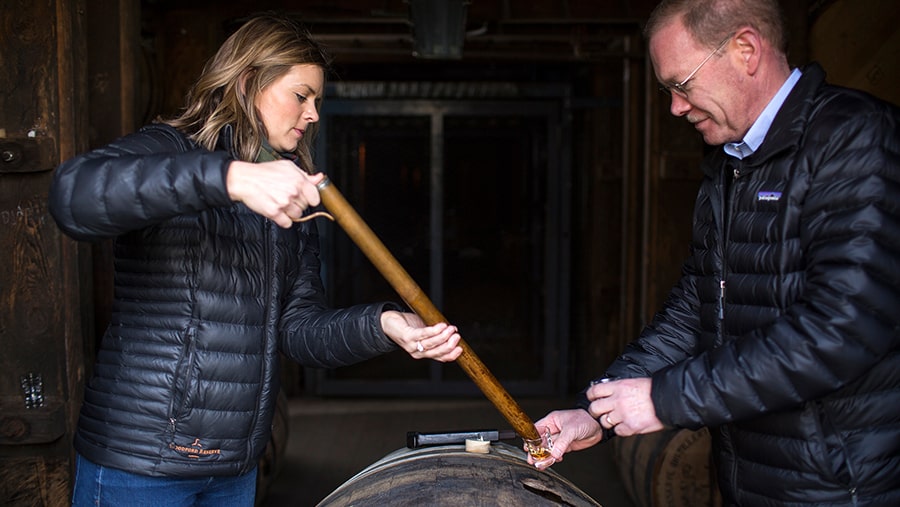 Distillers Elizabeth McCall and Chris Morris use a pipette to sample bourbon from a barrel 