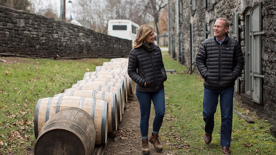 Elizabeth McCall and Chris Morris walk alongside lined up barrels outside on the grass
